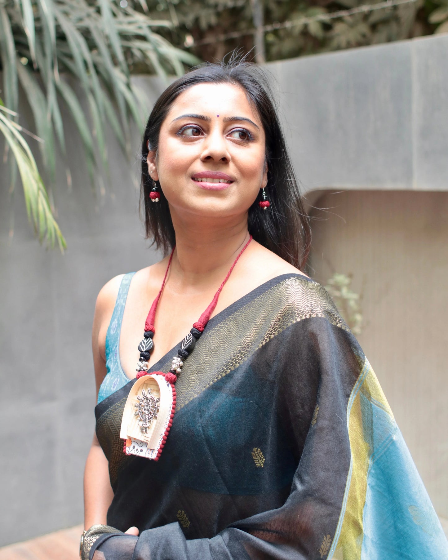 Woman wearing a traditional saree with a decorative pendant outdoors
