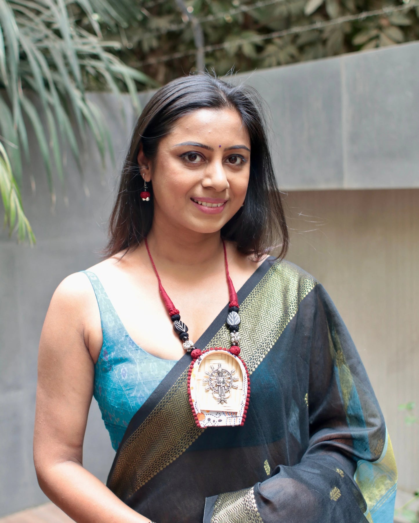 Woman wearing a saree with a decorative pendant outdoors