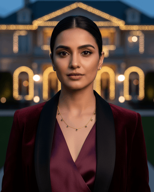Woman wearing a burgundy outfit with gold choker in front of a decorated house at night.
