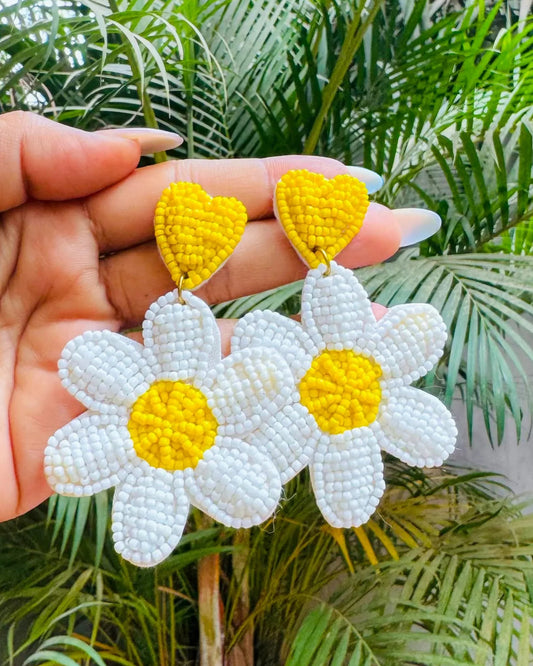 a pair of white flower-shaped earrings with yellow centers