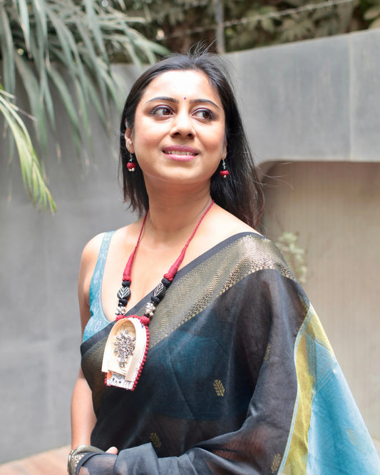 Woman wearing a traditional saree with a decorative pendant outdoors
